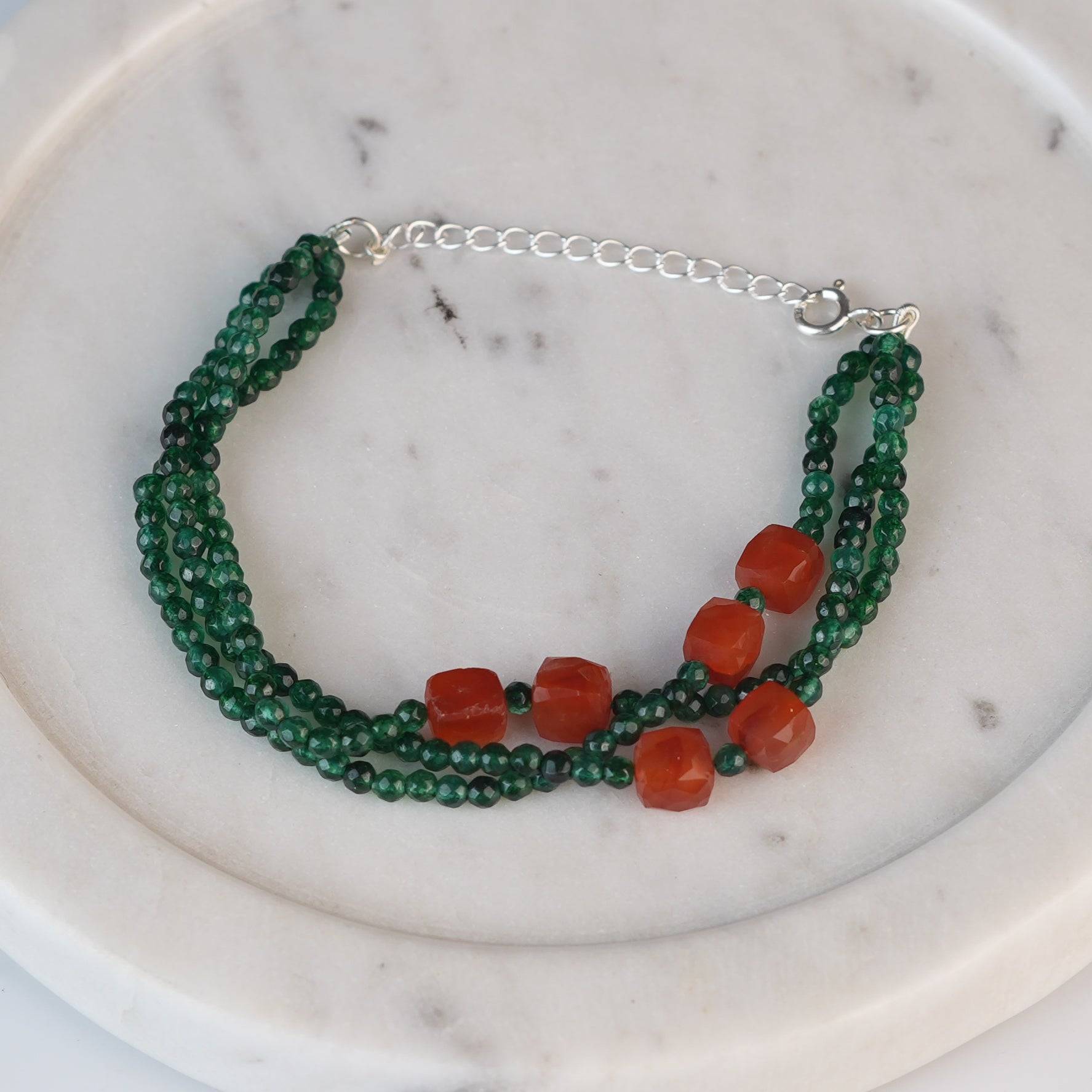 Flat-lay of a green onyx & Carnelian Silver Bracelet with natural gemstones and complementary handcrafted silver jewellery