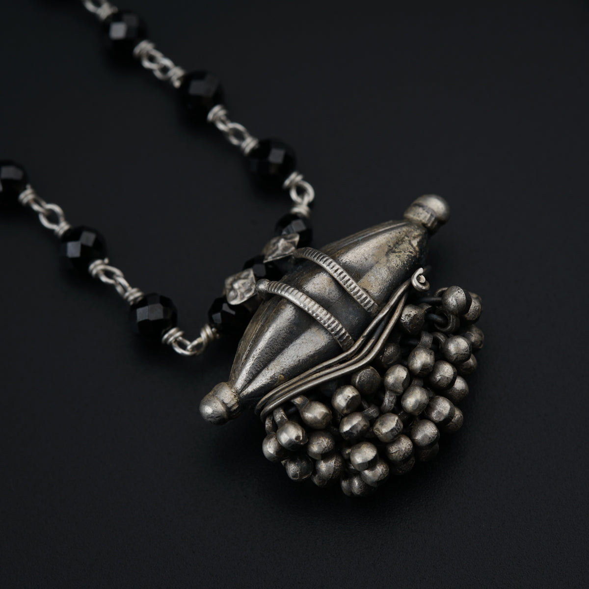 a necklace with a silver object hanging from it's side