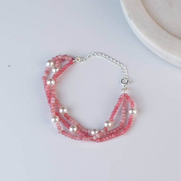 Flat-lay of a pink jade & Pearl Silver Bracelet with natural pink jade, pearls, and complementary silver jewelry