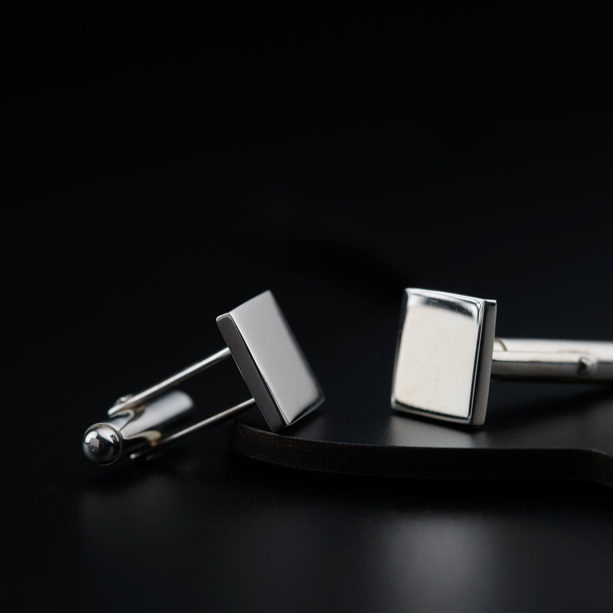 a pair of square cufflinks on a black surface