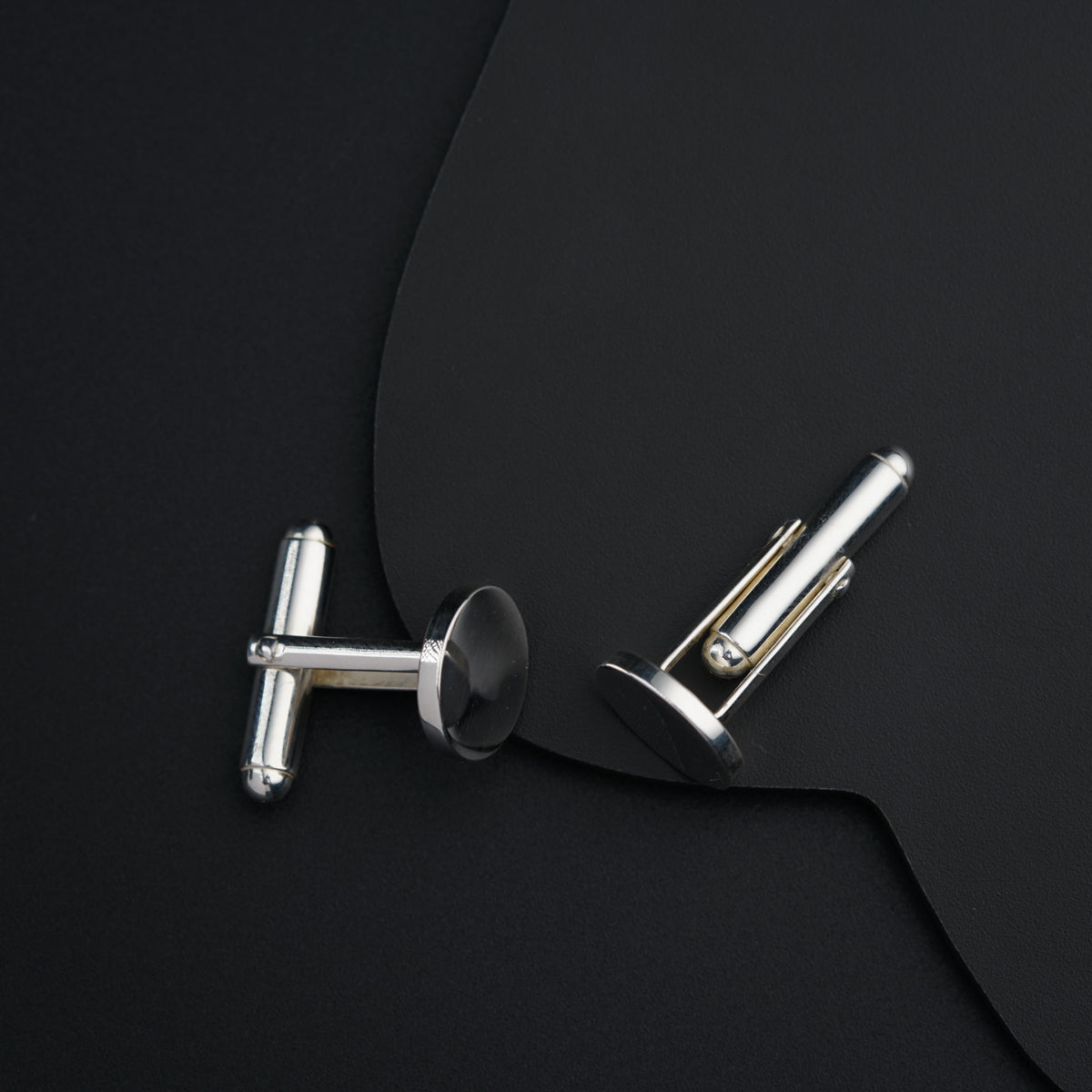 a pair of silver cufflinks on a black background