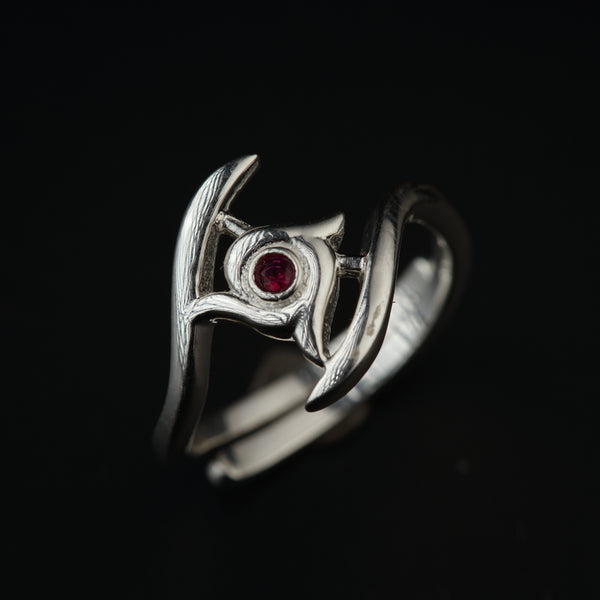 a close up of a silver ring with a red stone