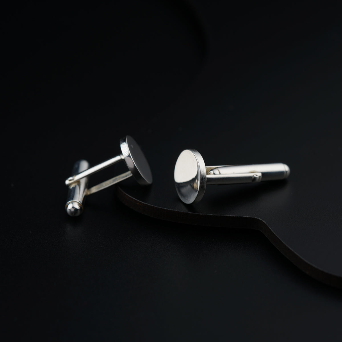 a pair of silver cufflinks on a black surface