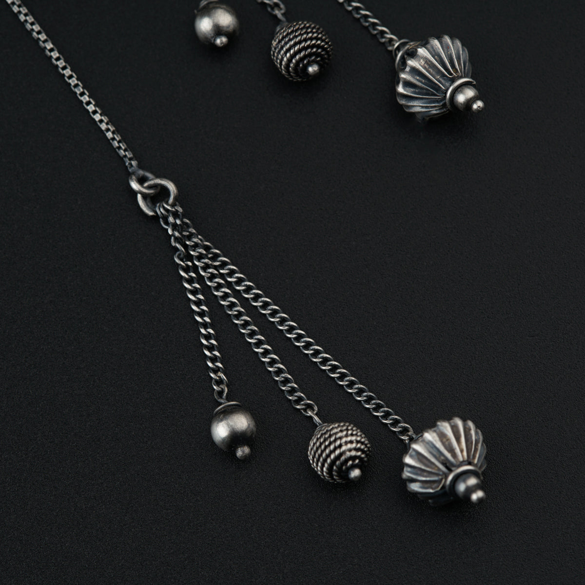 a close up of a necklace and earrings on a black surface