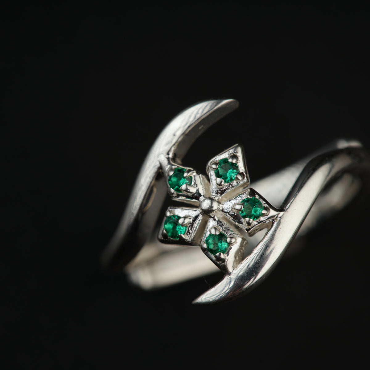 a close up of a ring with green stones
