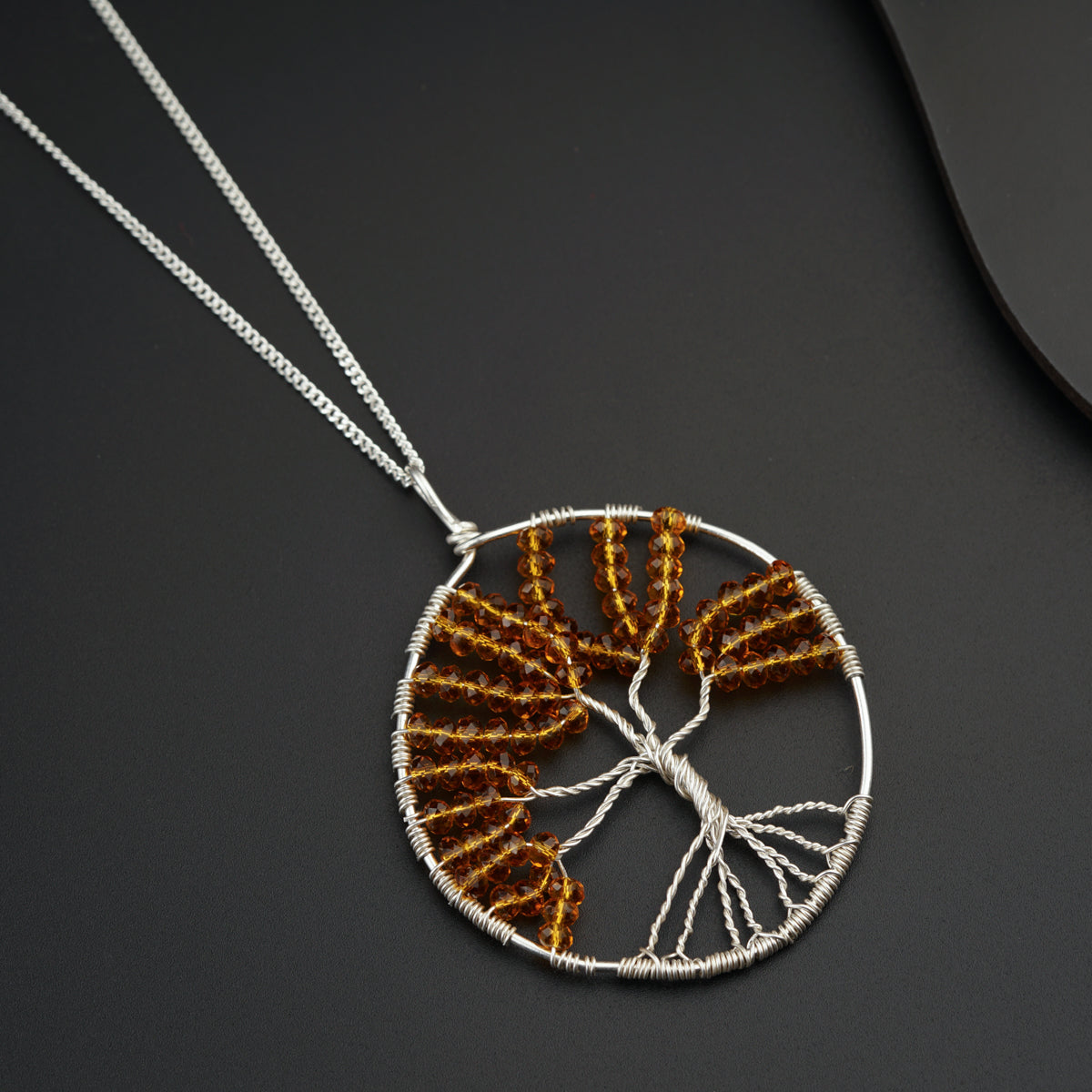 a tree of life pendant is shown on a black surface