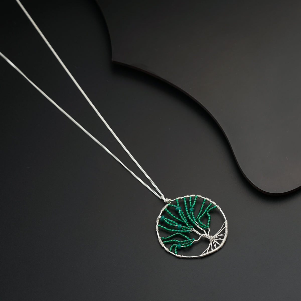 a necklace with a green leaf on it