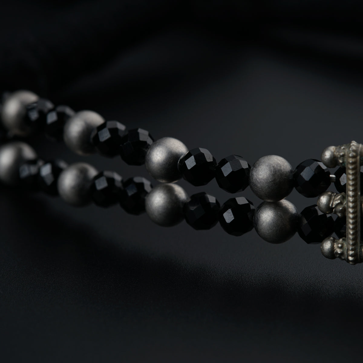 a close up of a beaded necklace on a black background