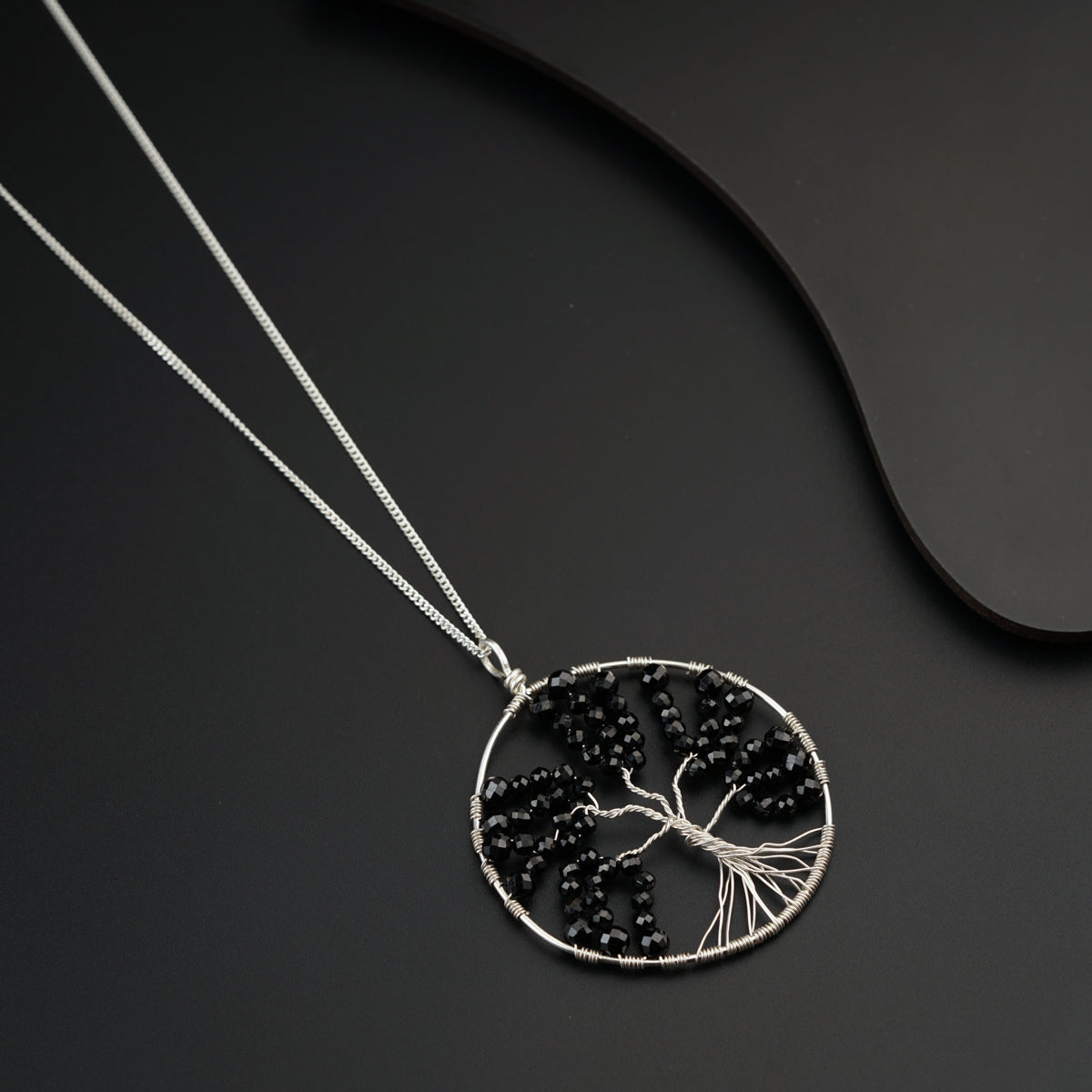 a tree of life pendant is shown on a black surface