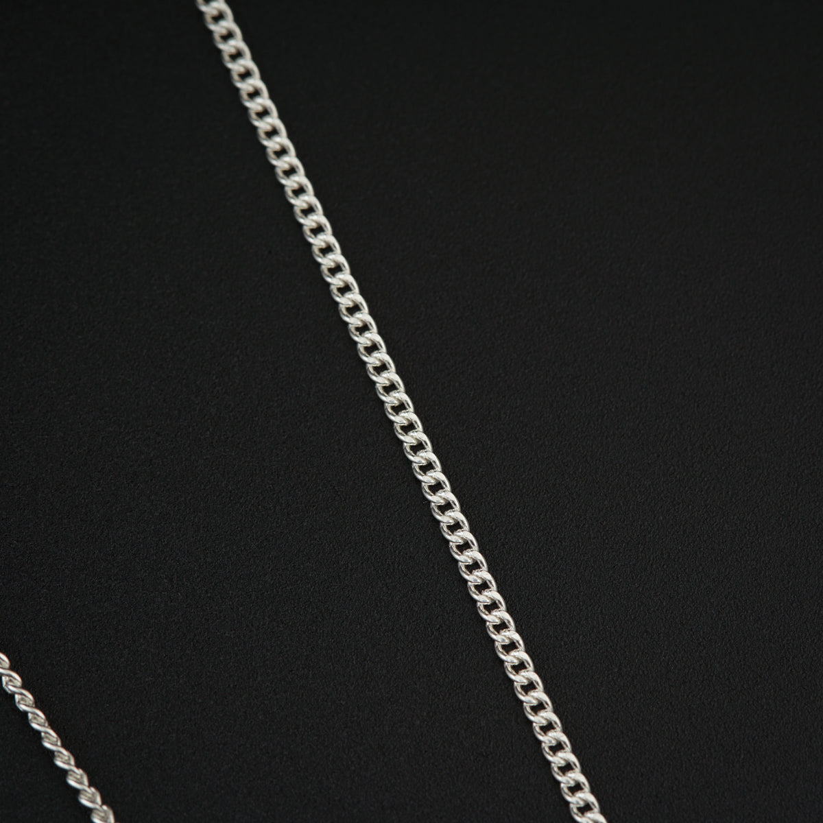 a silver chain is shown on a black surface
