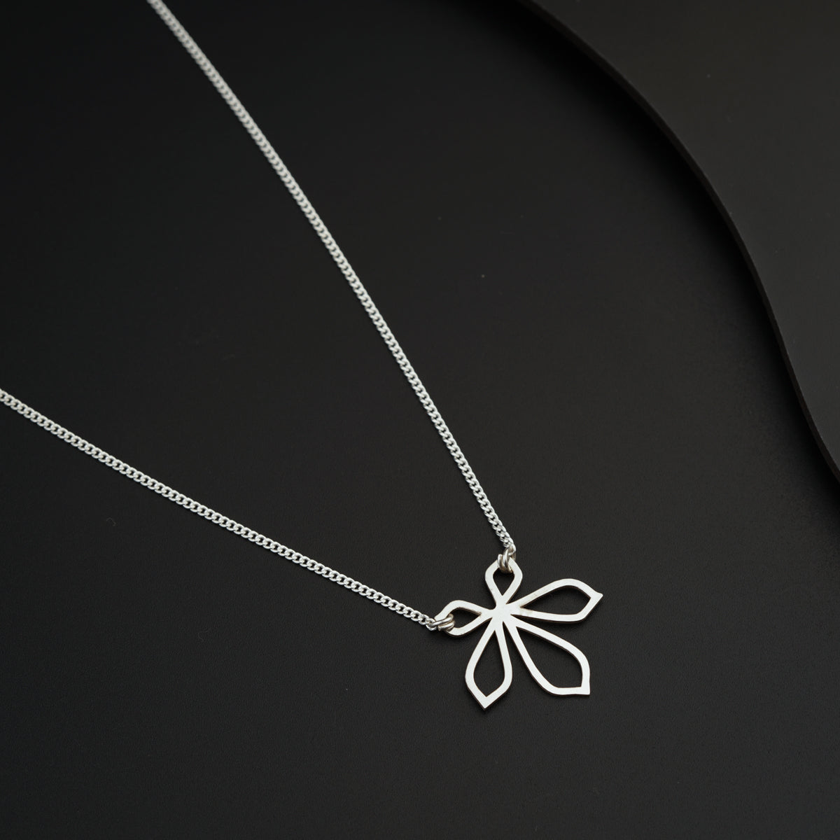 a silver necklace with a flower on it