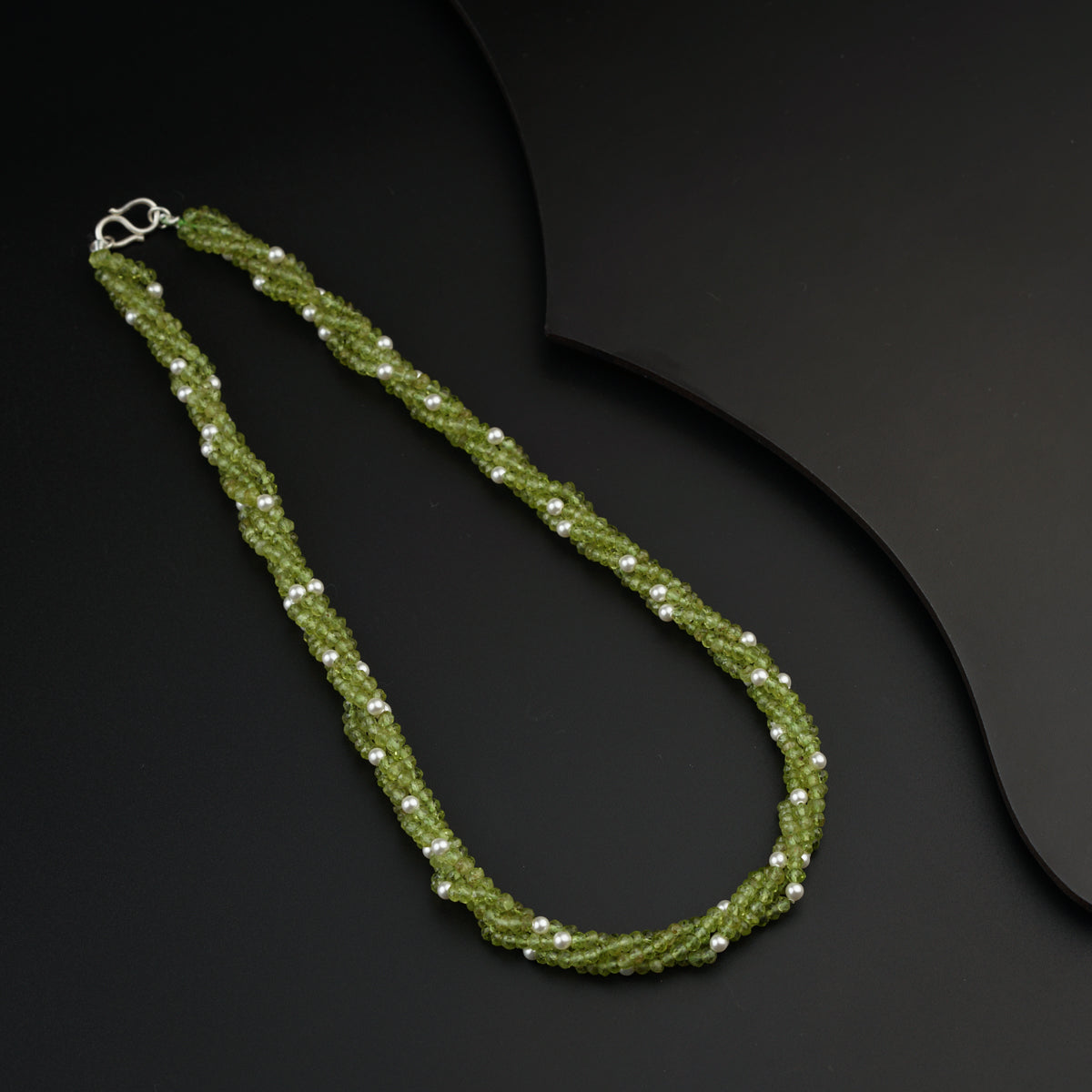 a green beaded necklace on a black surface