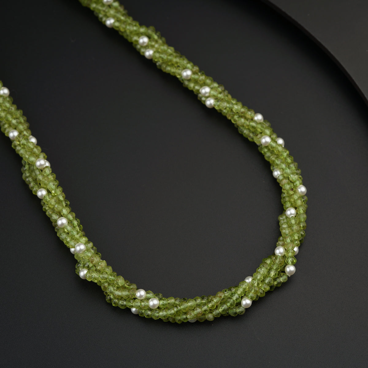 a green beaded necklace on a black plate