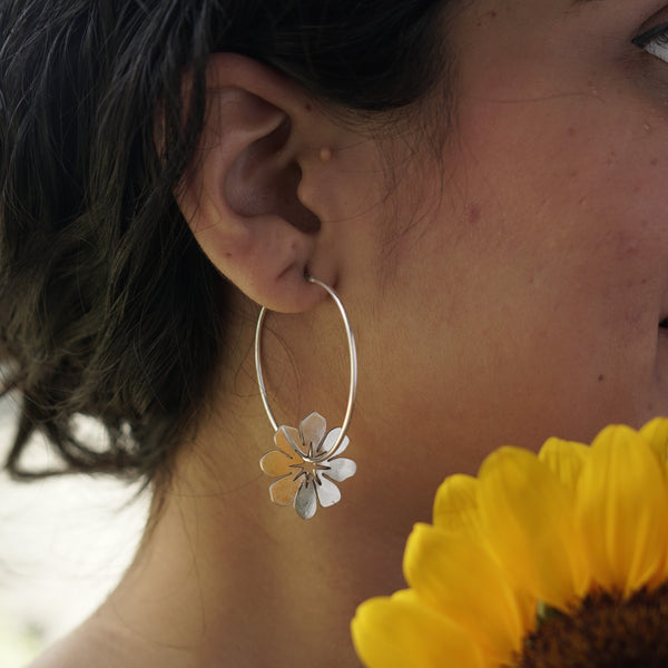 Silver flower hoop earring on ear