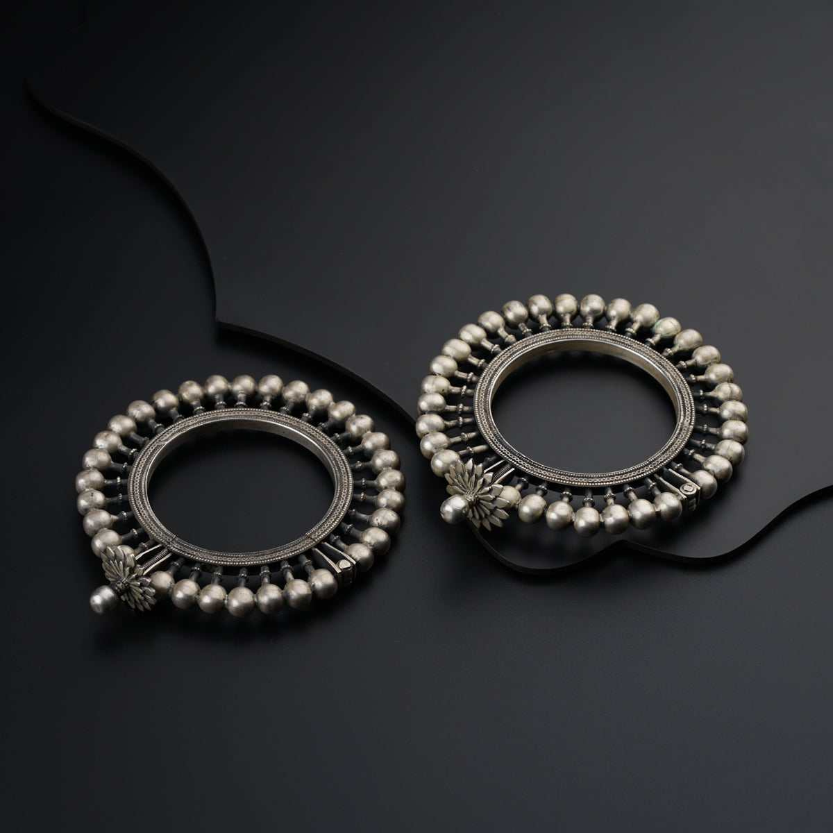 a pair of silver earrings sitting on top of a black surface