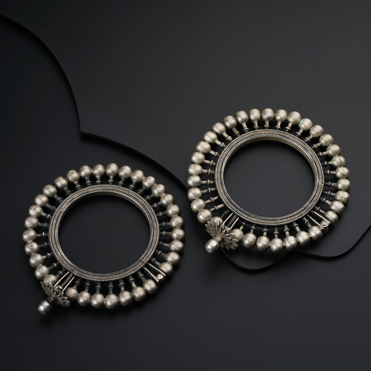 a pair of silver earrings on a black surface