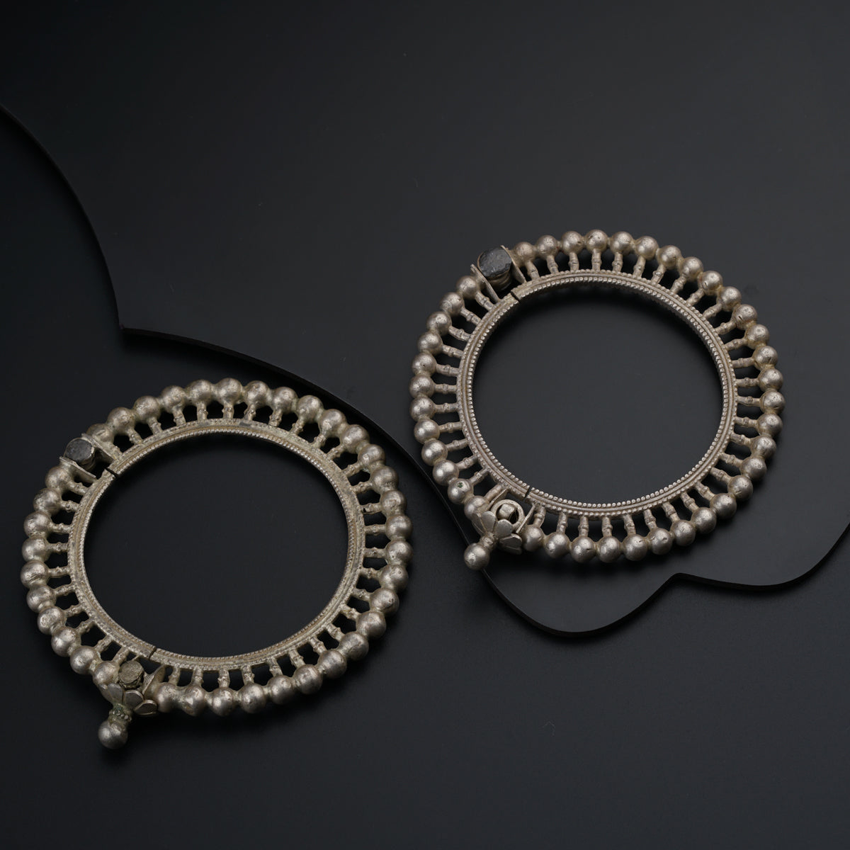 a pair of silver hoop earrings on a black surface