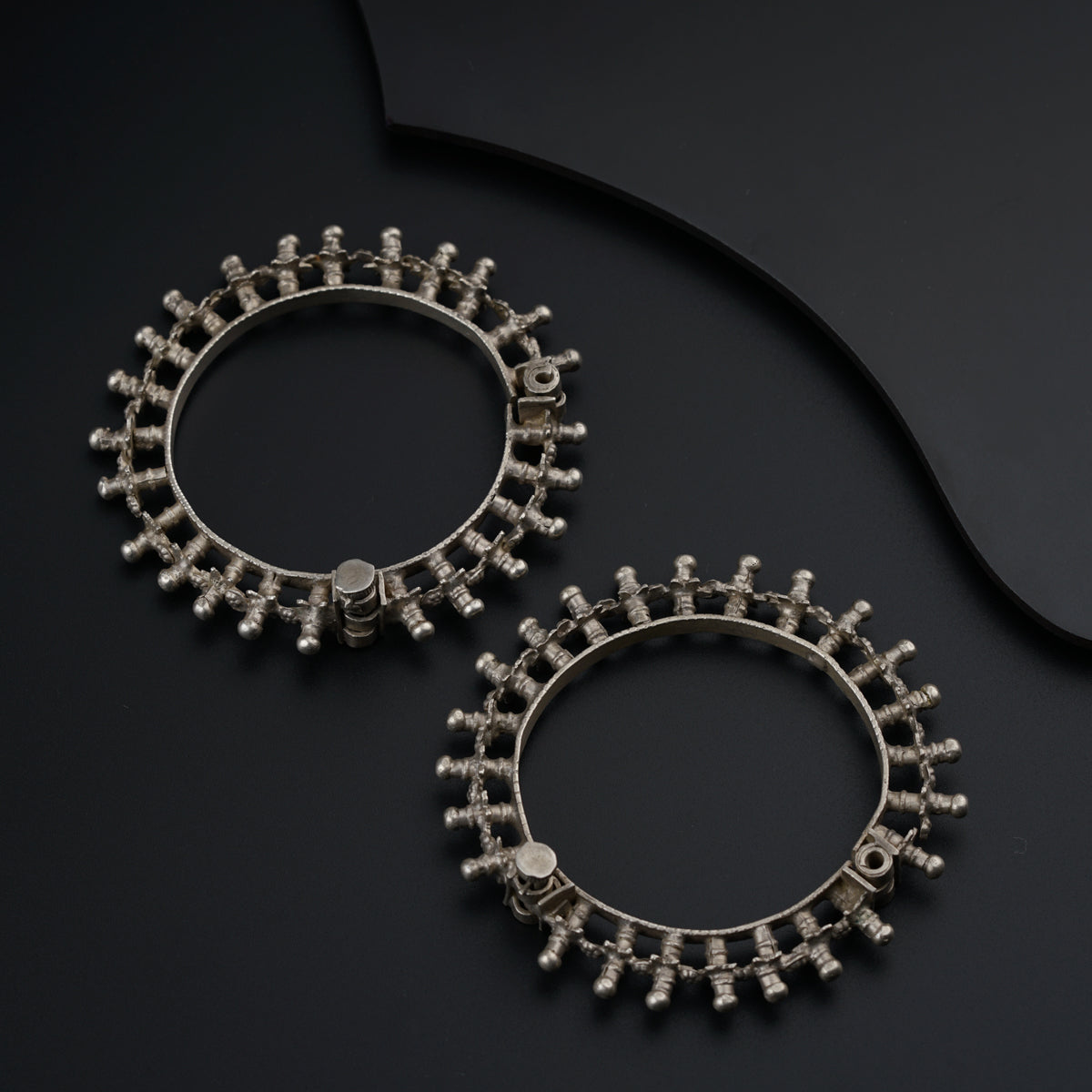 a pair of silver hoop earrings on a black surface