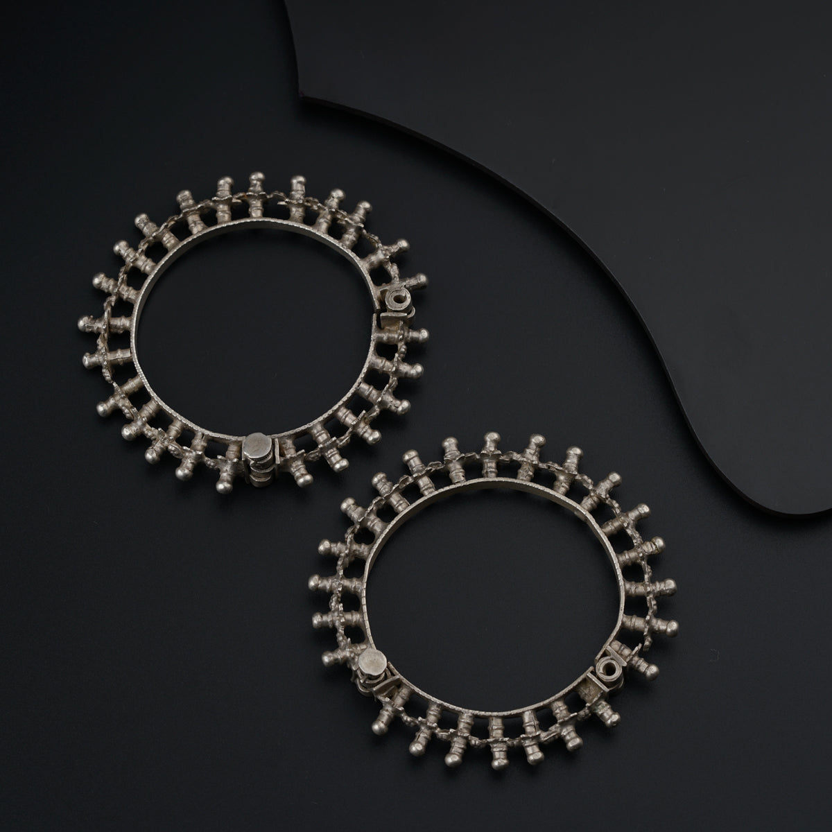 a pair of silver hoop earrings on a black surface