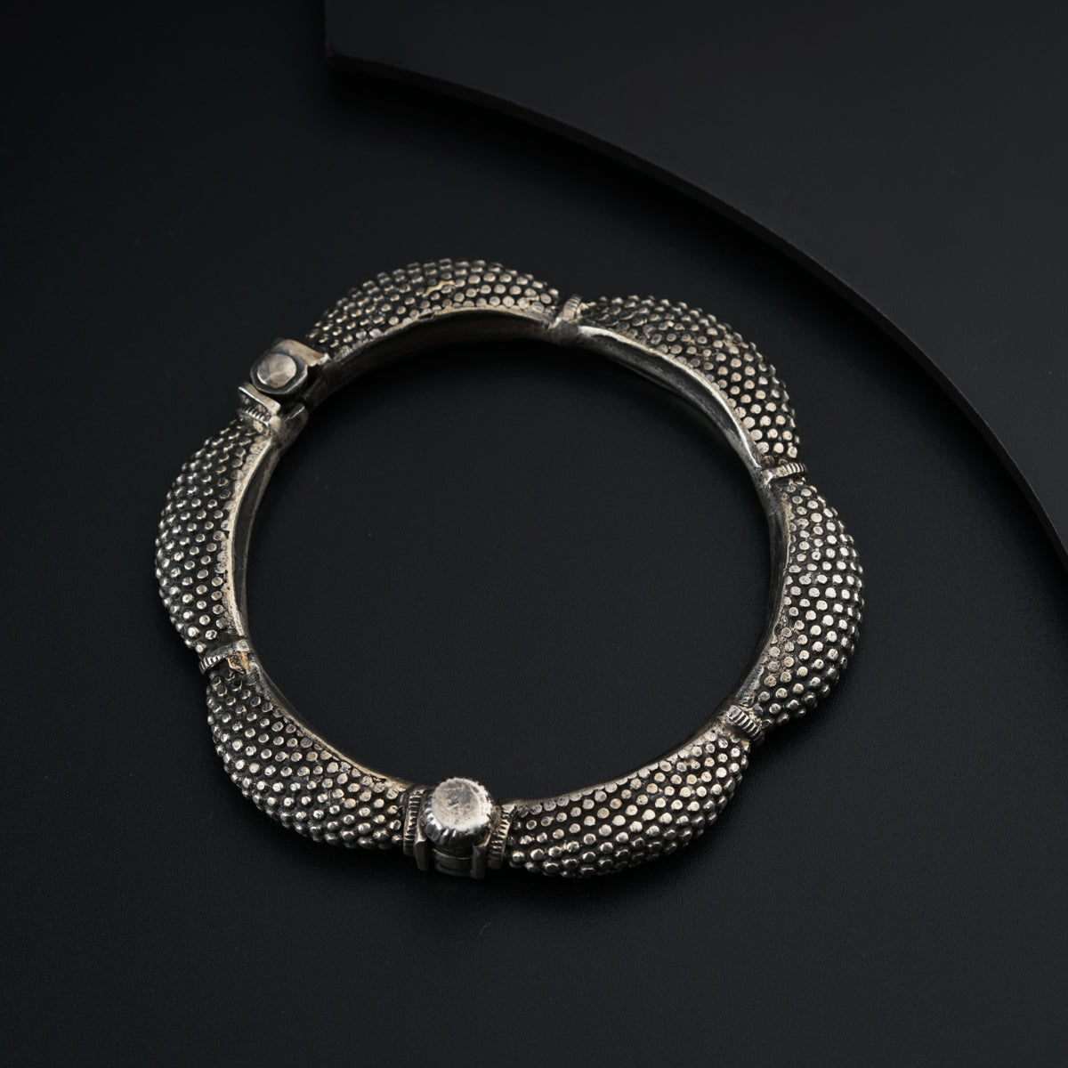 a close up of a silver bracelet on a black surface