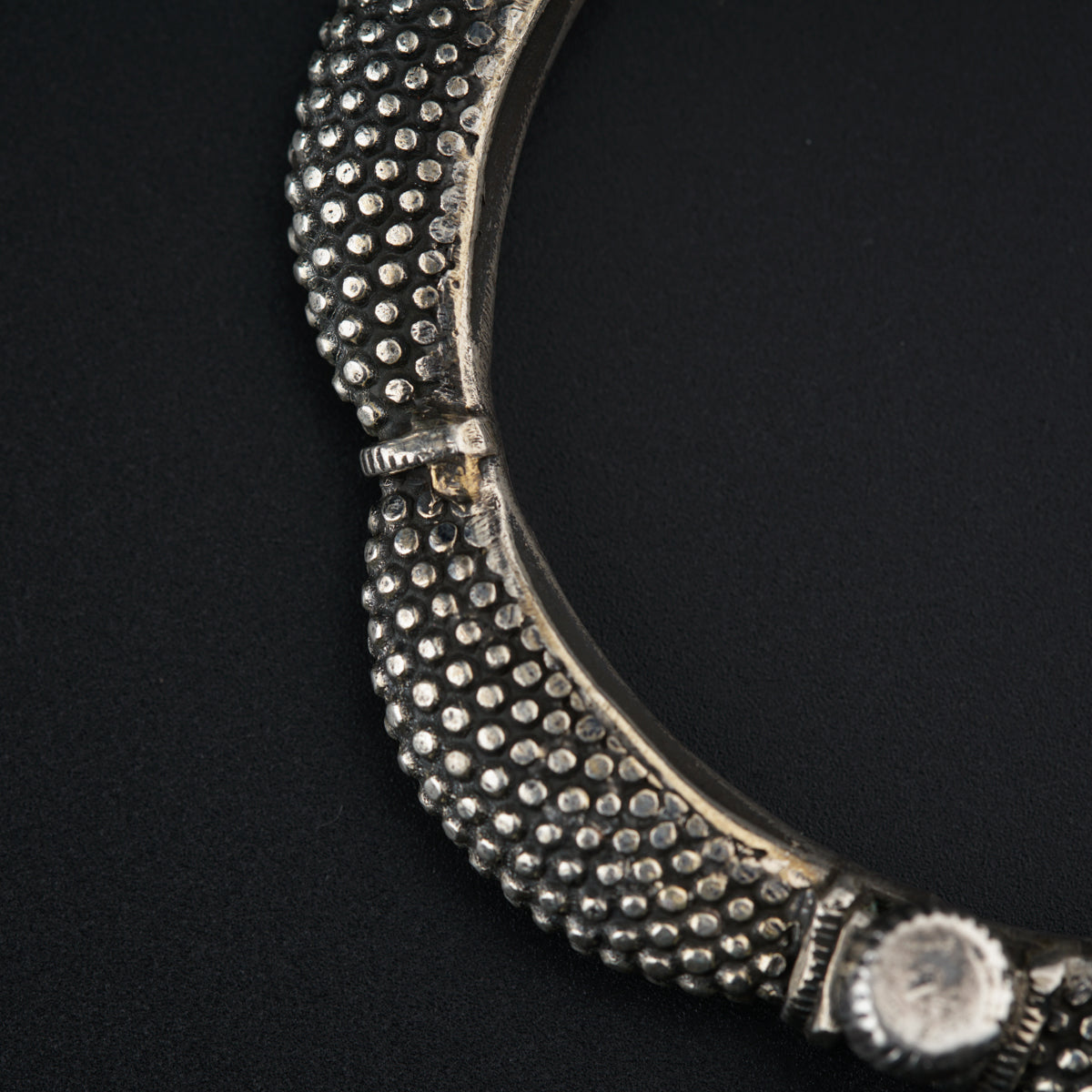 a close up of a silver necklace on a black surface