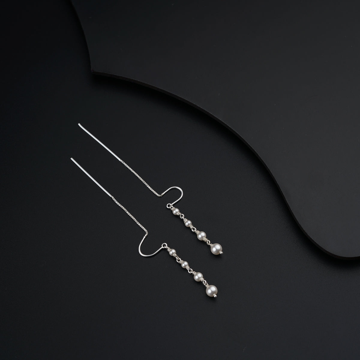 a pair of silver earrings on a black surface