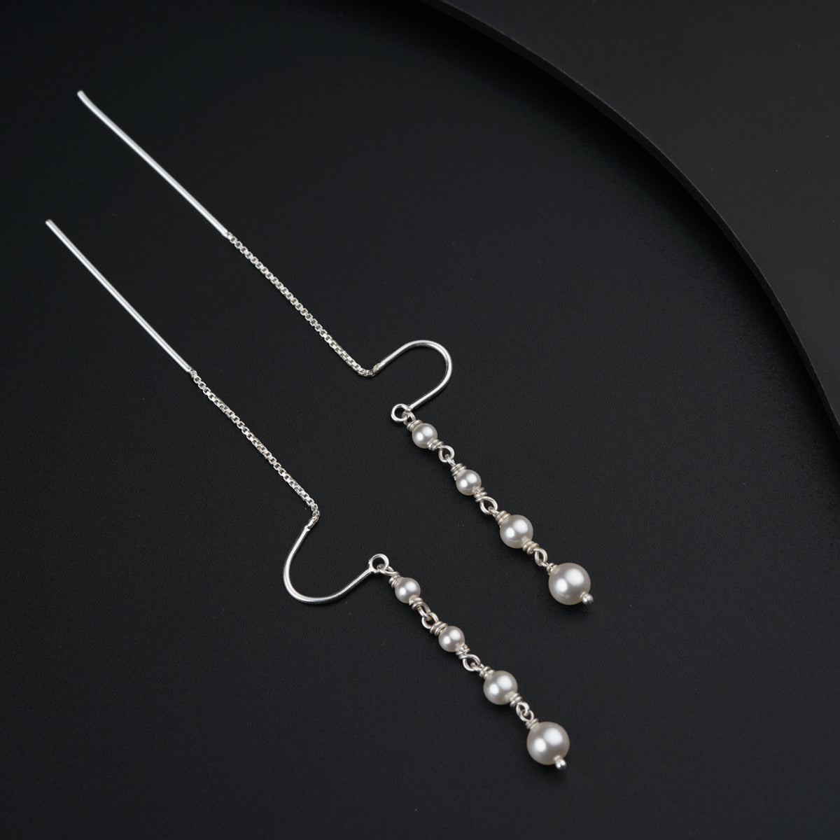 a pair of earrings with pearls hanging from them