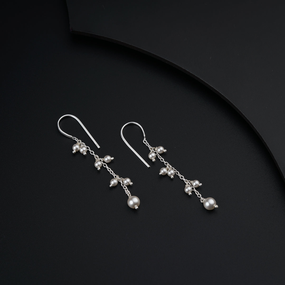 a pair of earrings with pearls hanging from them