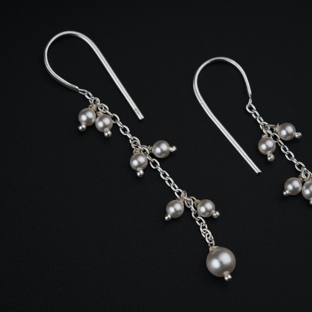 a pair of earrings with pearls hanging from them