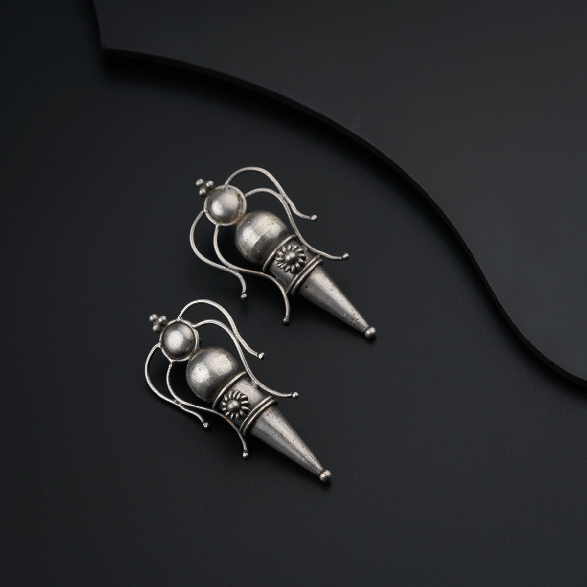 a pair of silver earrings sitting on top of a black surface