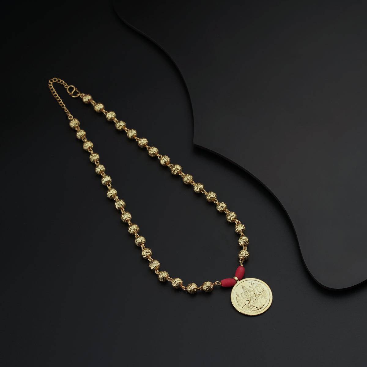 a gold necklace with a medallion on a black background