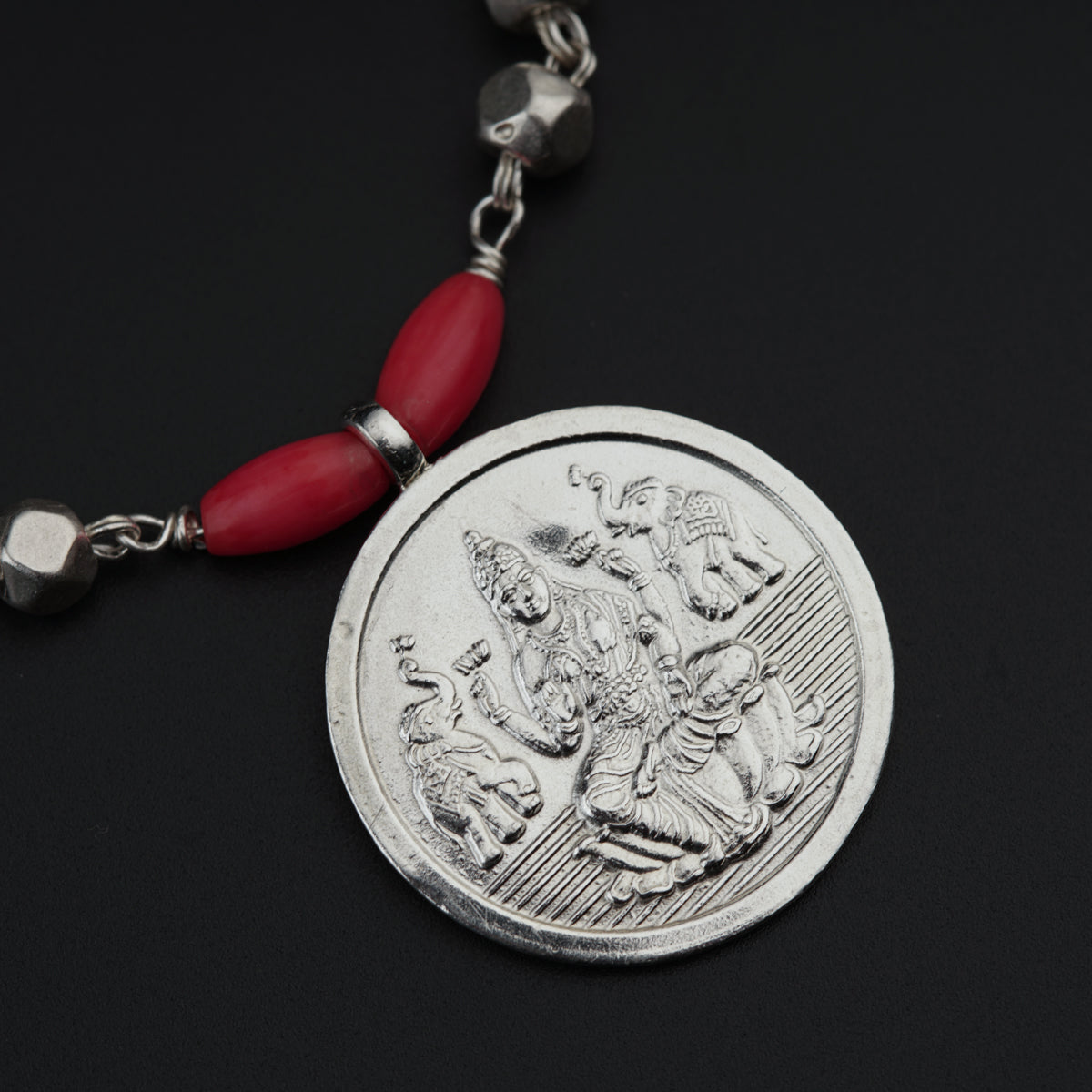 a red beaded necklace with a coin on it