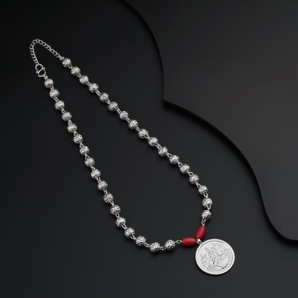 a necklace with a coin on a black surface