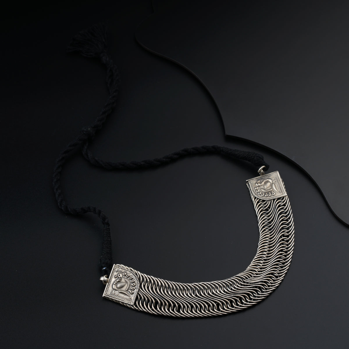 a silver necklace on a black background