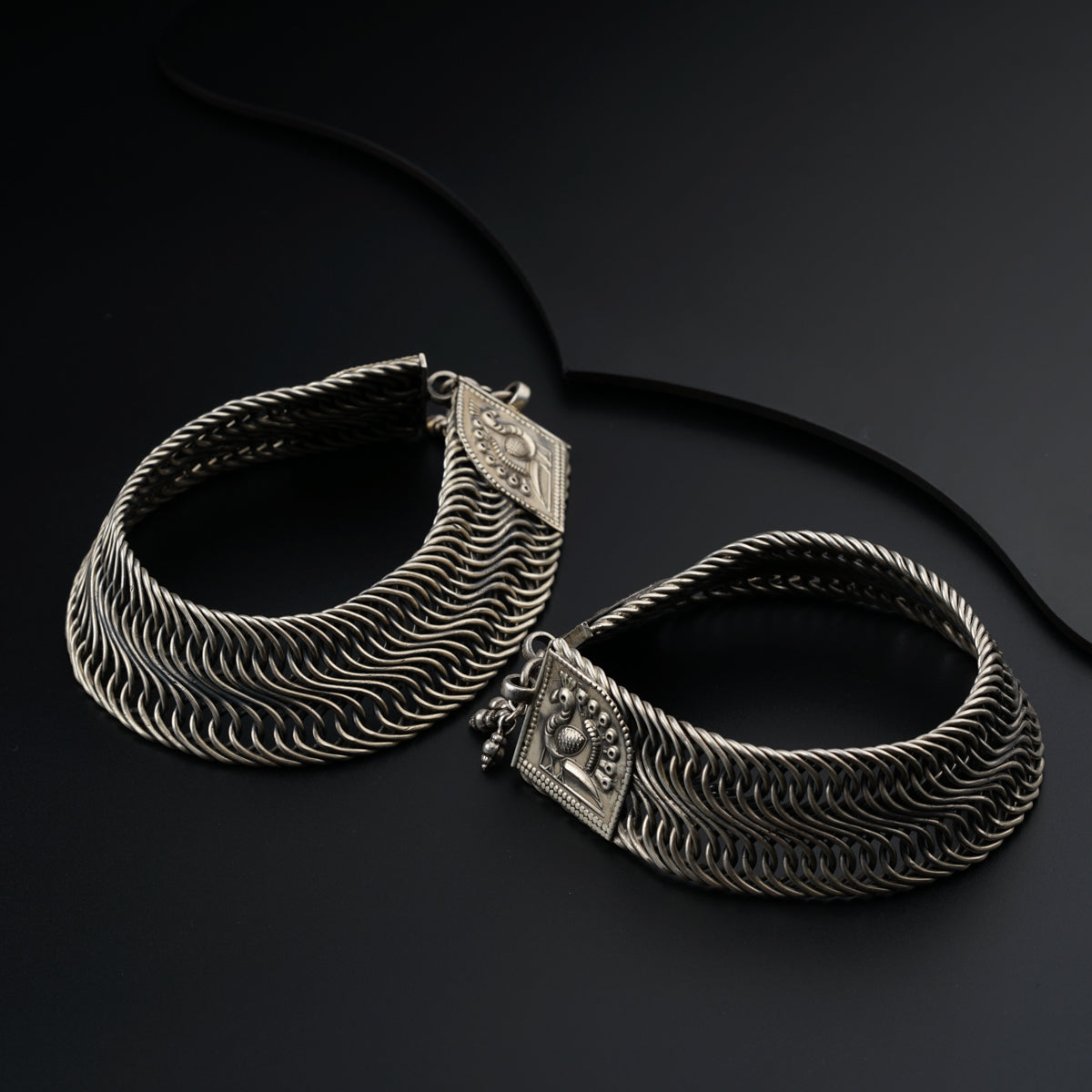 a pair of silver bracelets on a black surface