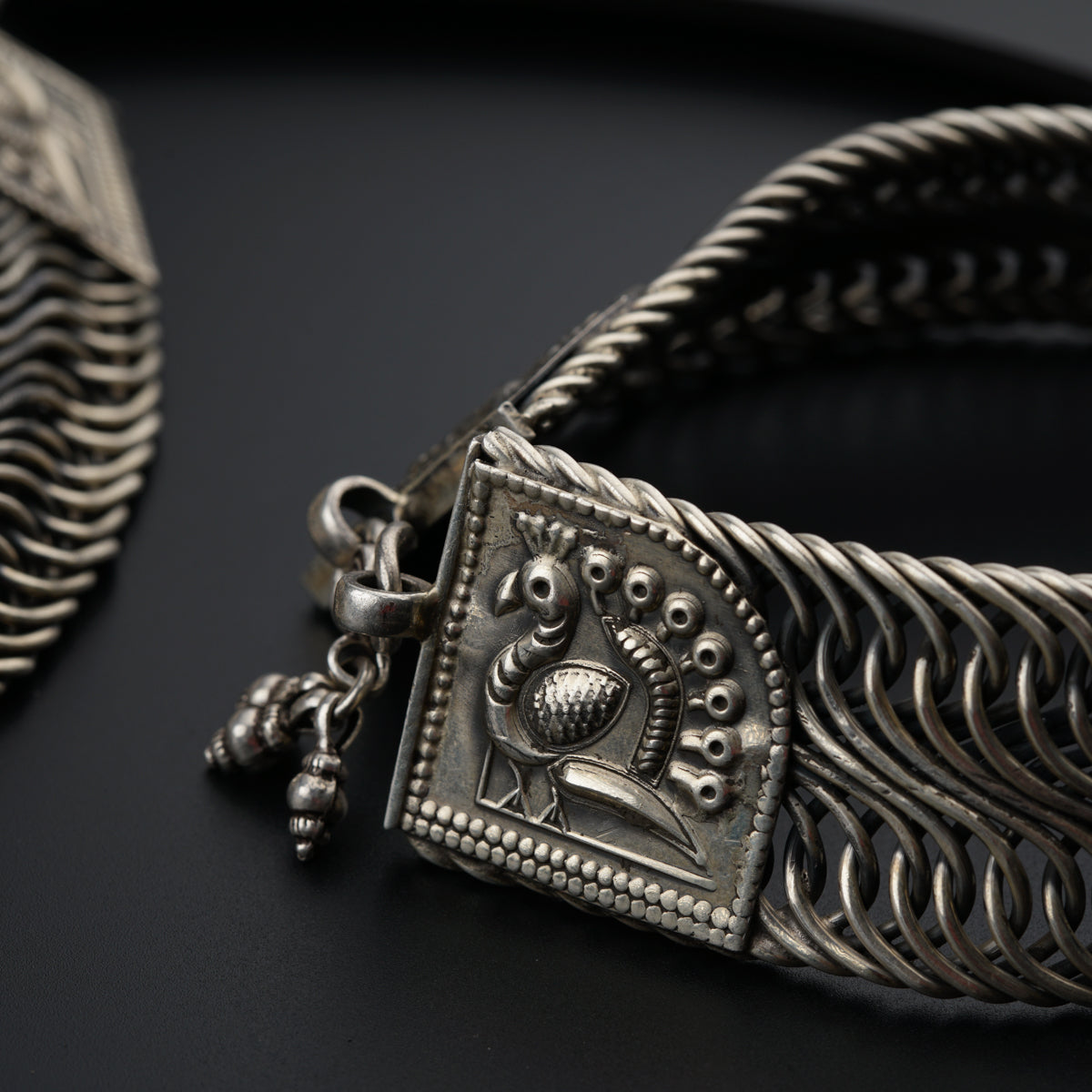 a close up of a silver bracelet on a black surface