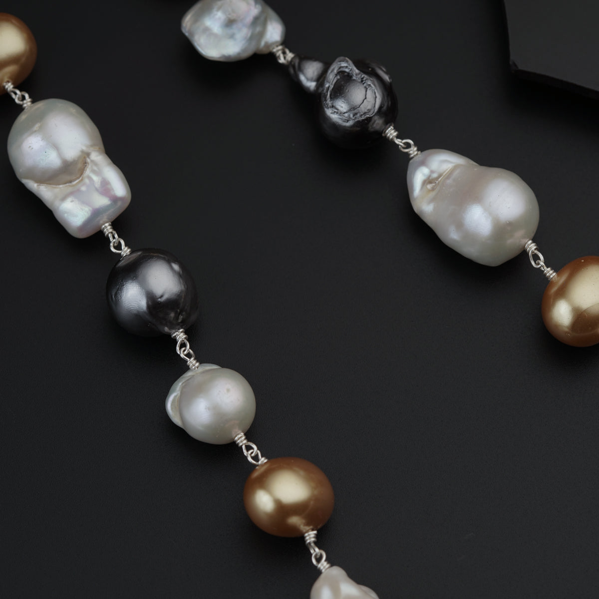 a long necklace with pearls on a black surface