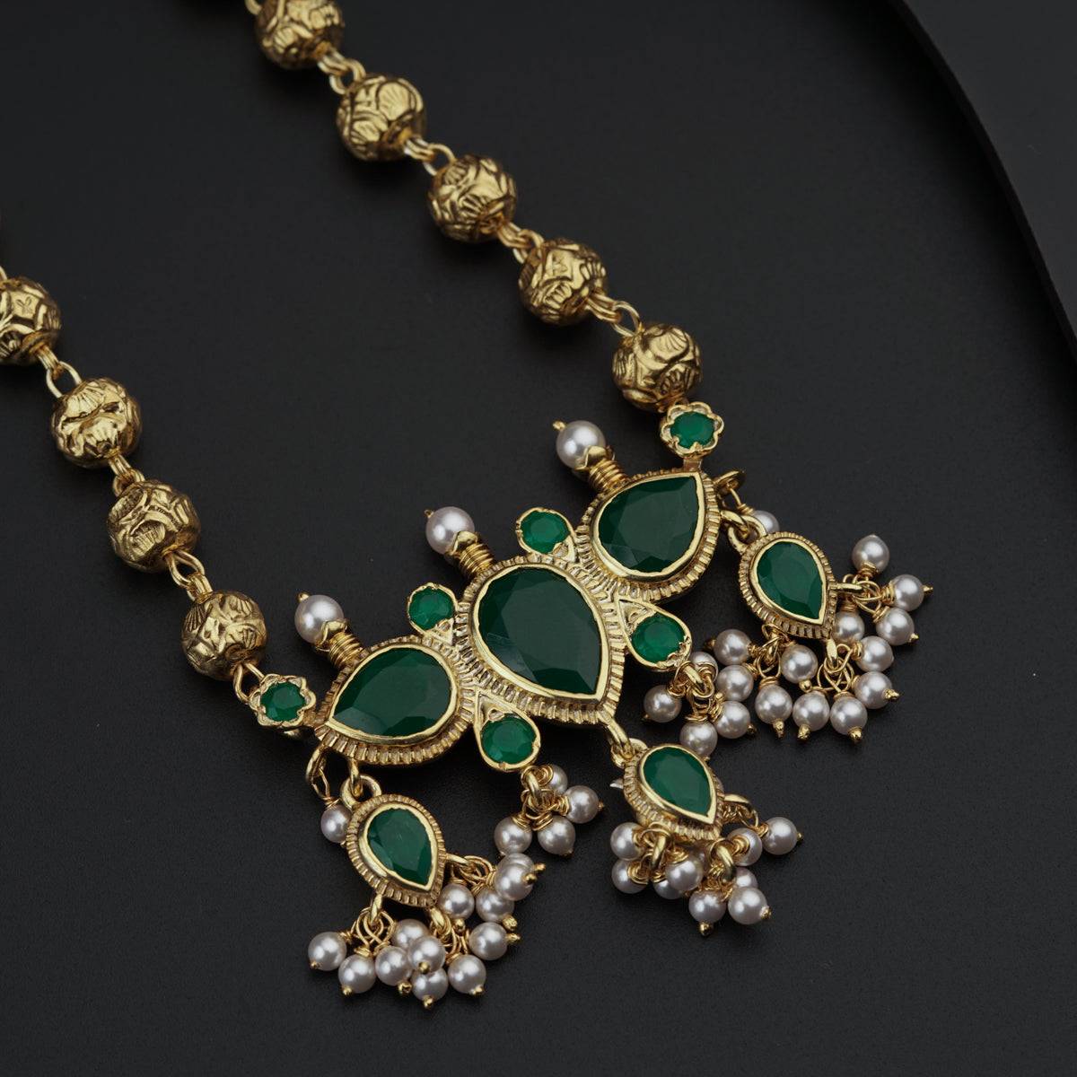 a green and gold necklace with pearls