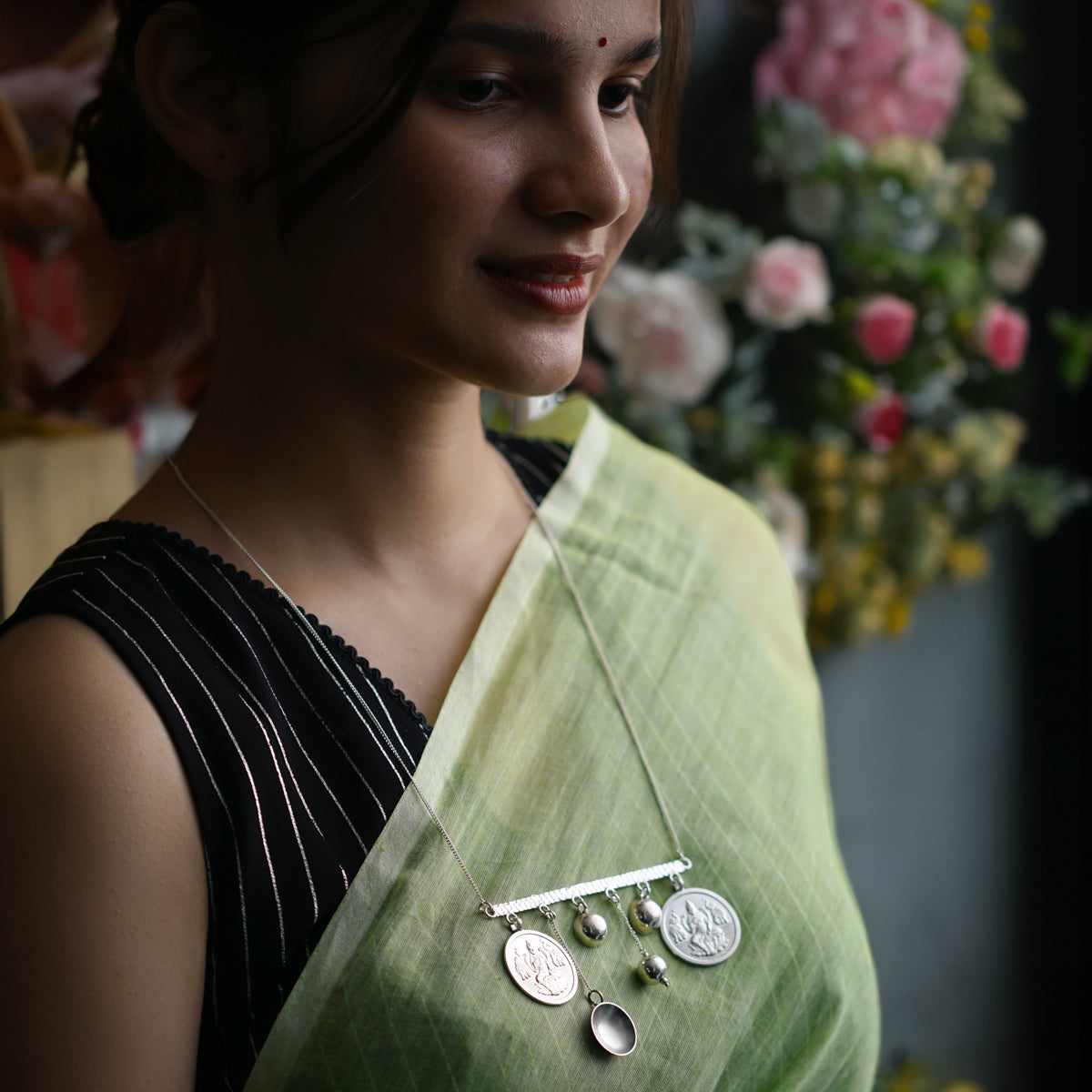 a woman wearing a green sari and a necklace
