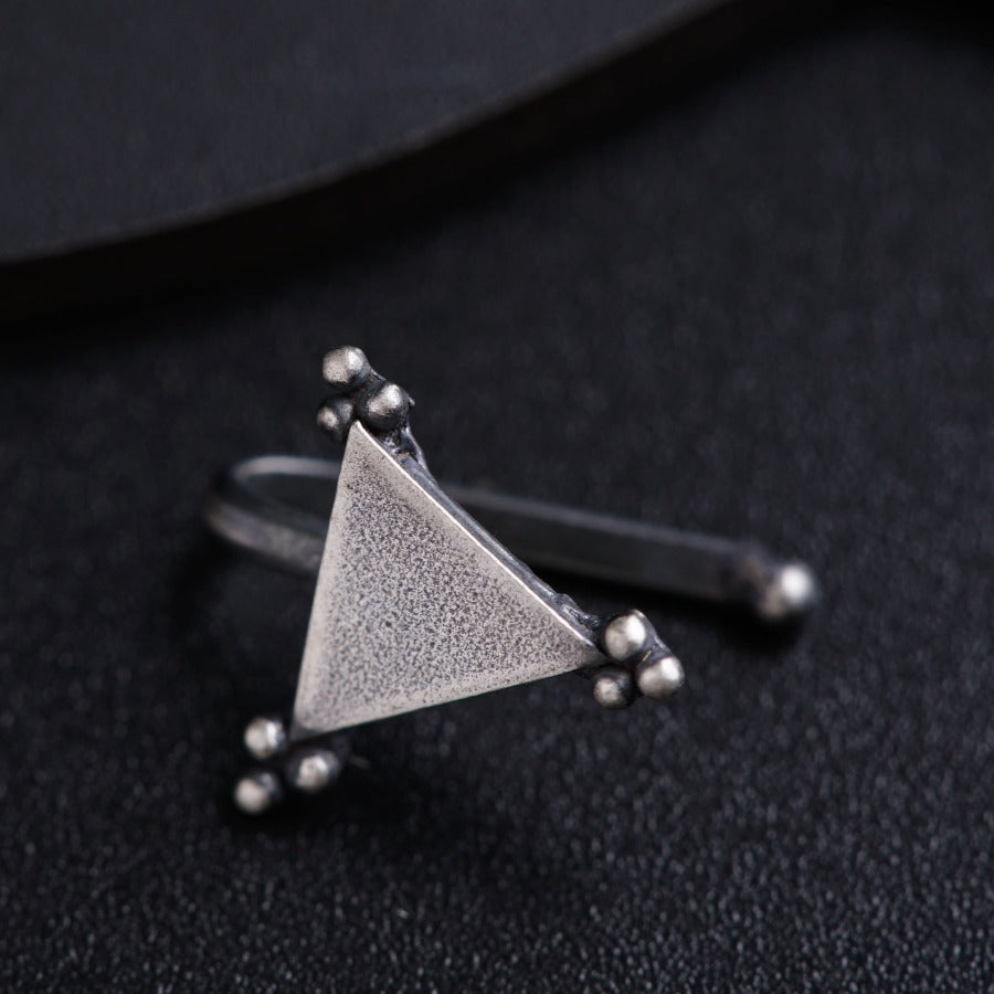 a triangle shaped ring sitting on top of a black surface