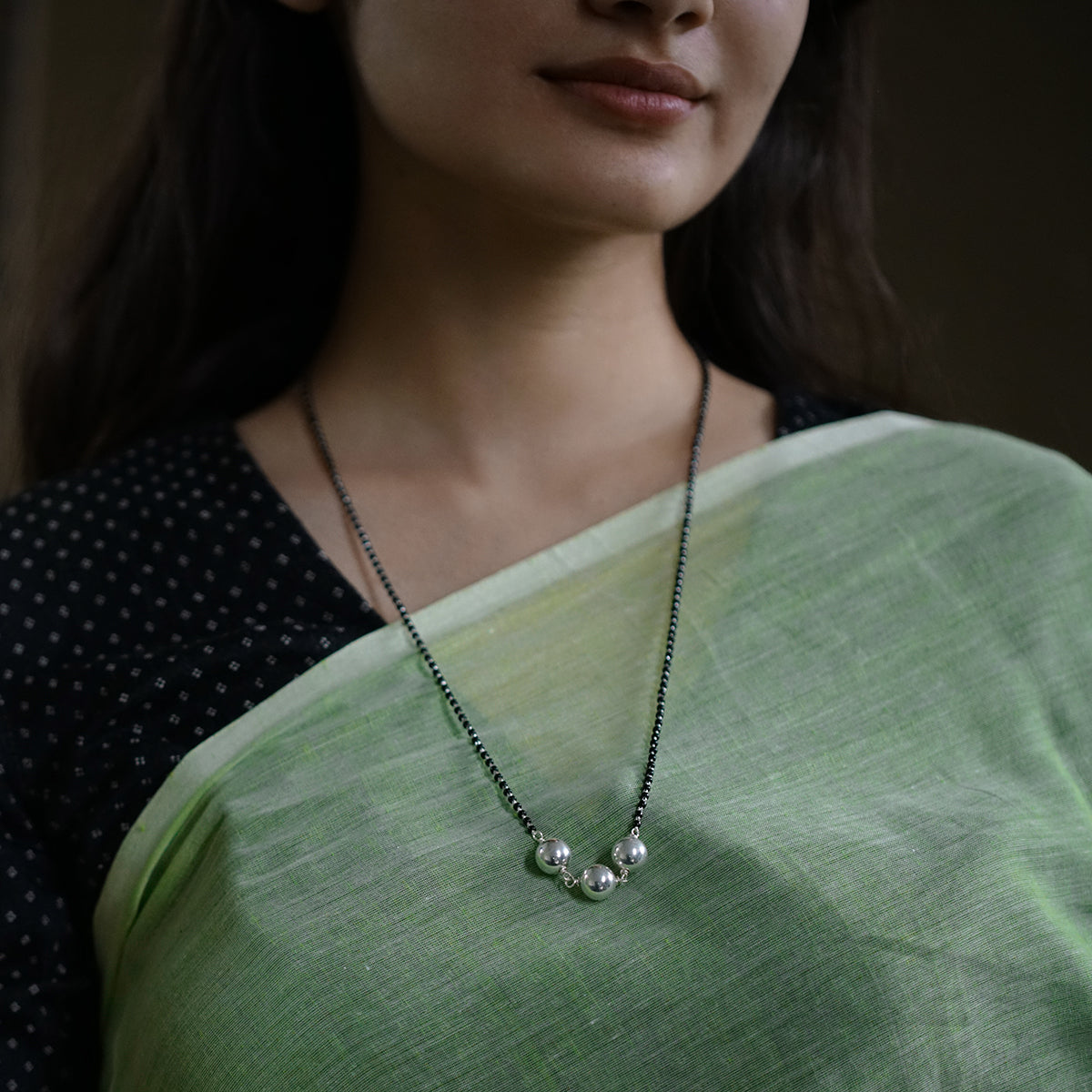 a woman wearing a green shirt and a necklace