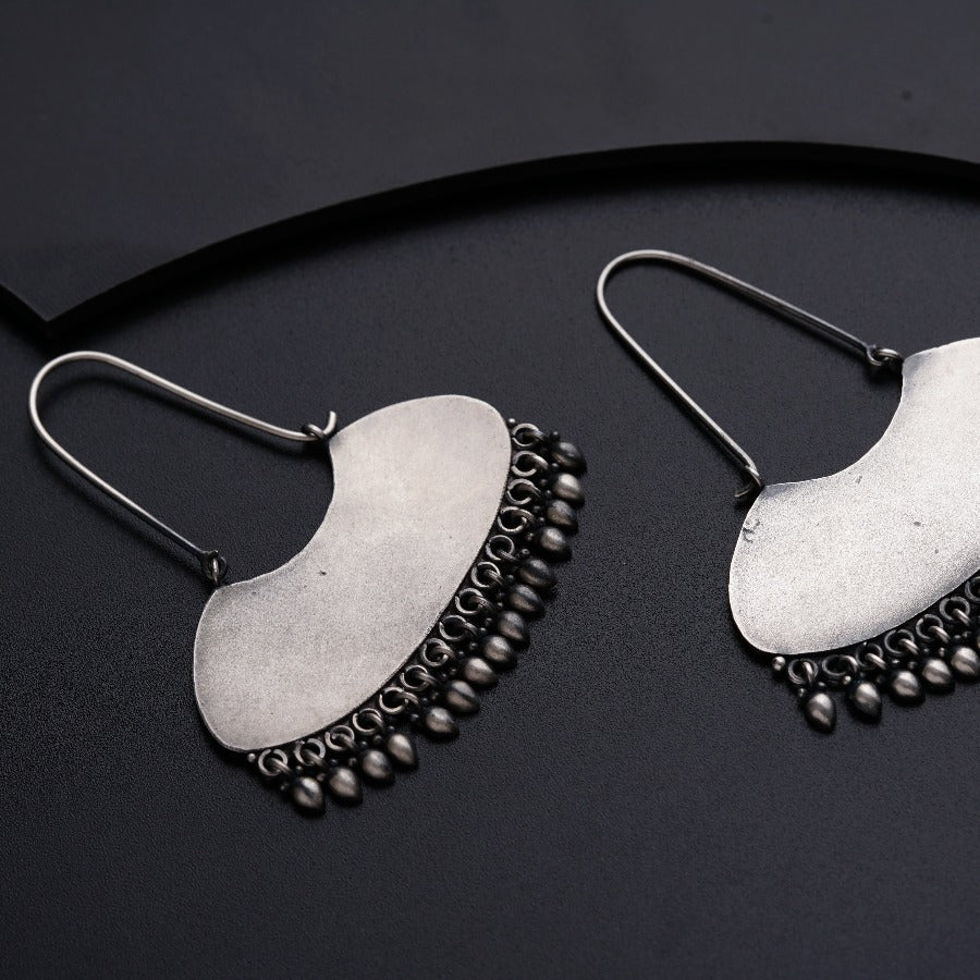 a pair of silver earrings on a black surface