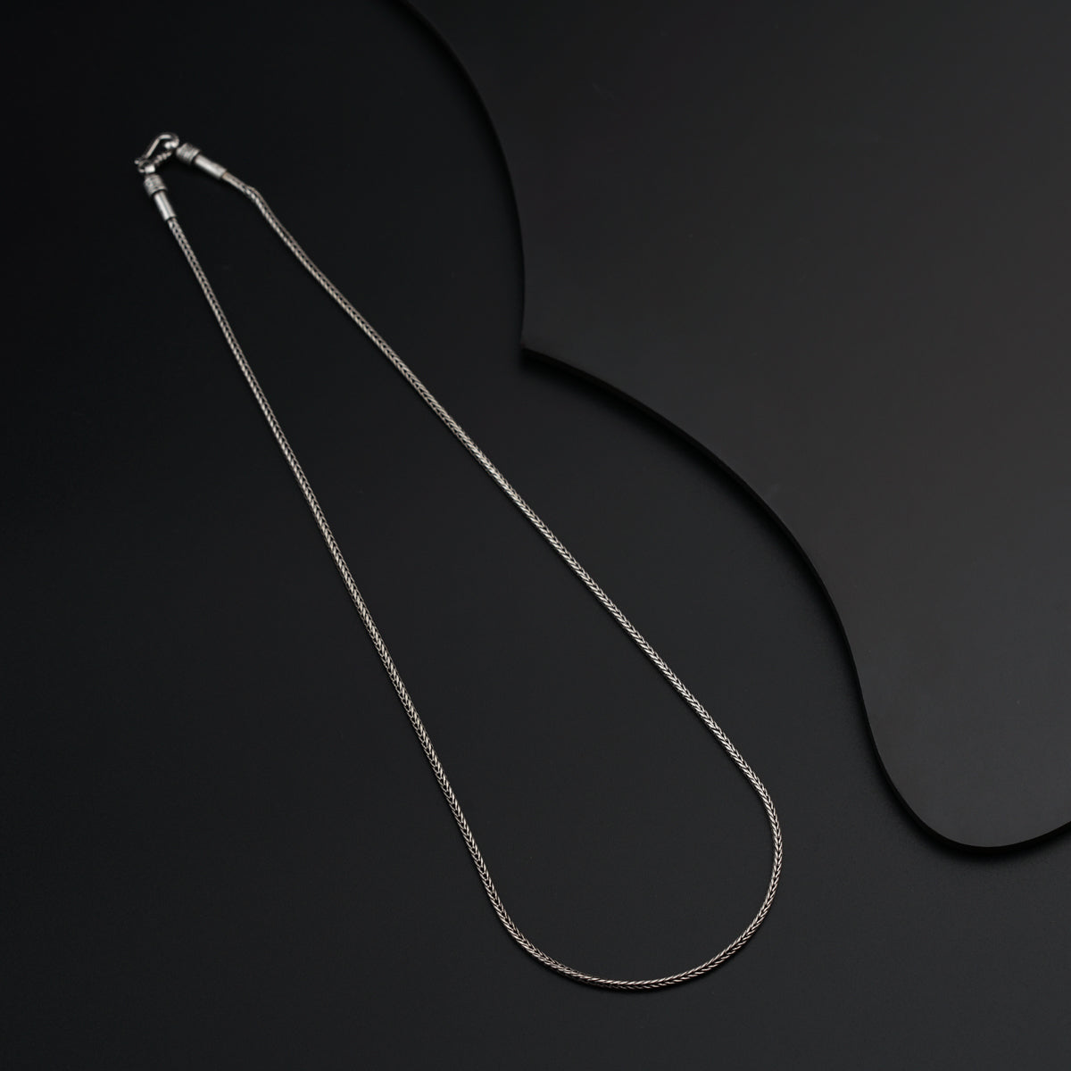 a silver necklace on a black background