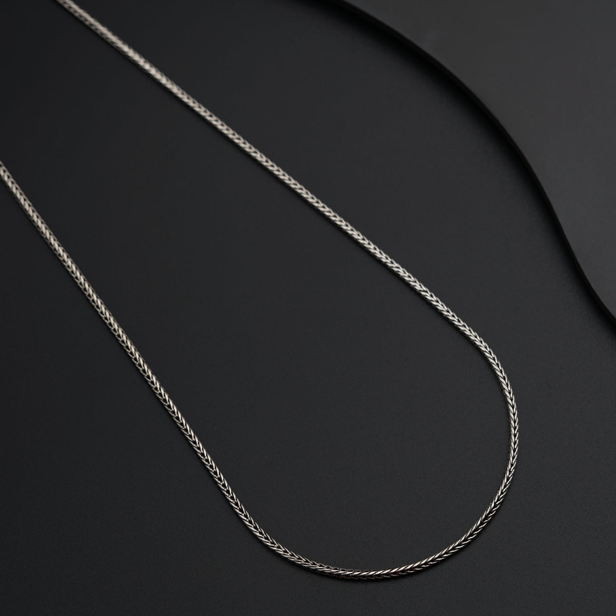 a silver chain on a black surface