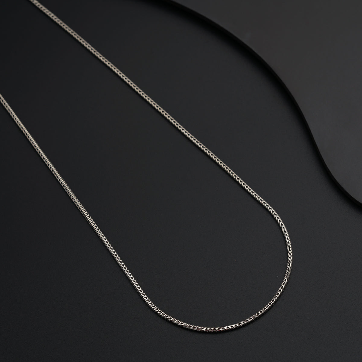 a silver chain is laying on a black surface