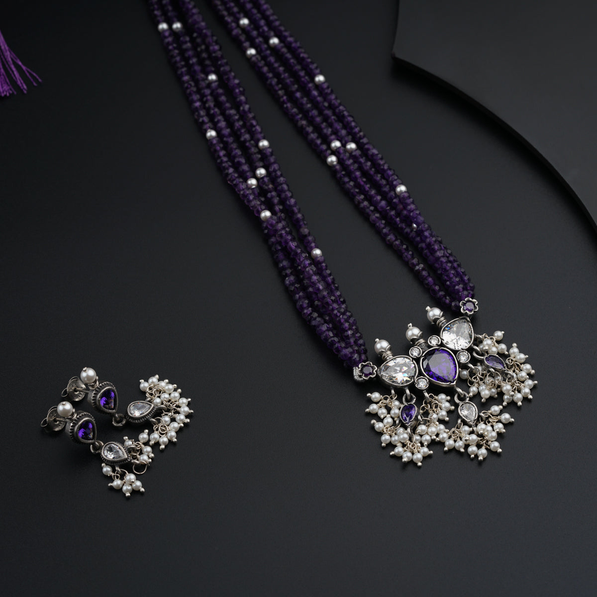 a purple necklace and earring with pearls