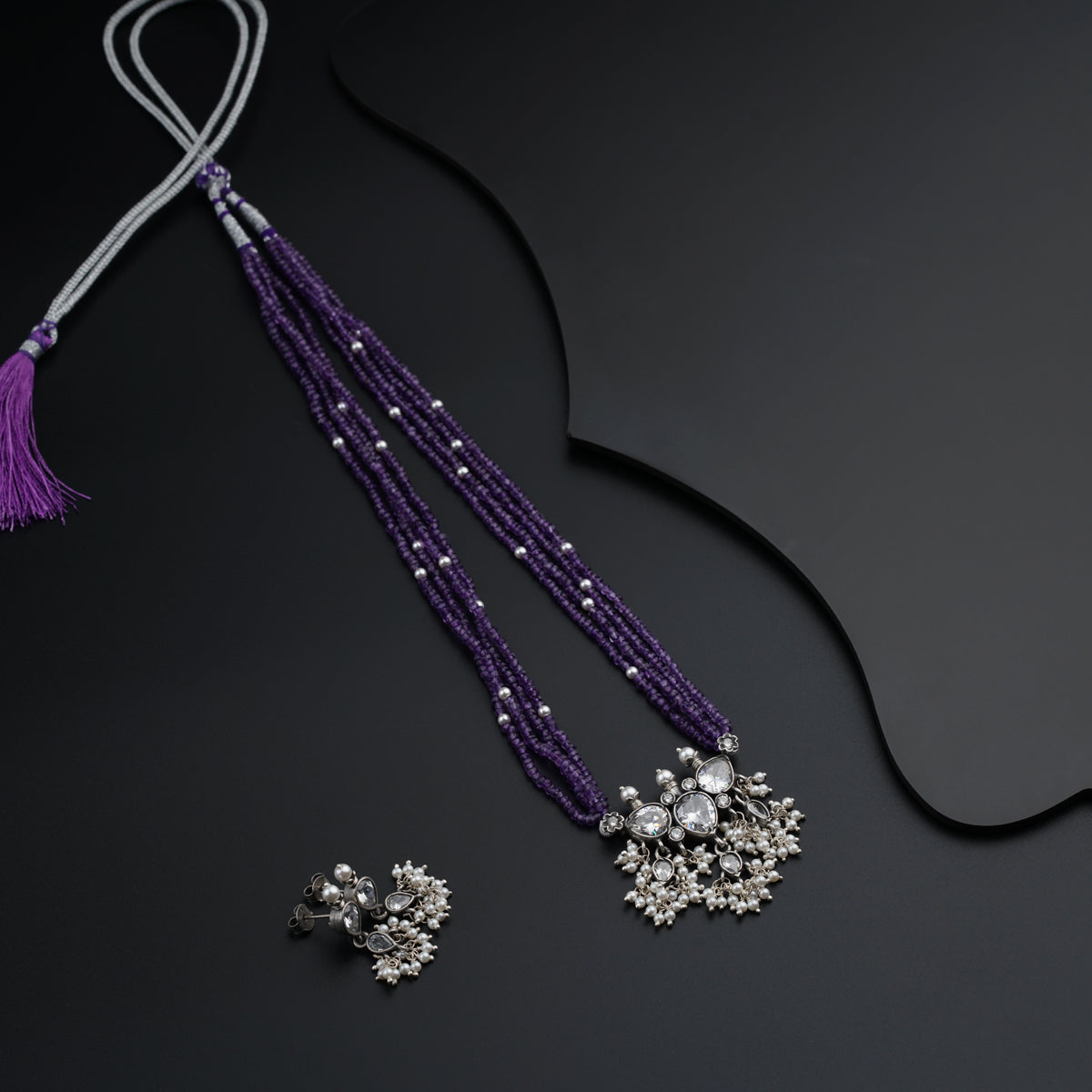 a purple necklace with a tassel and a pair of earrings