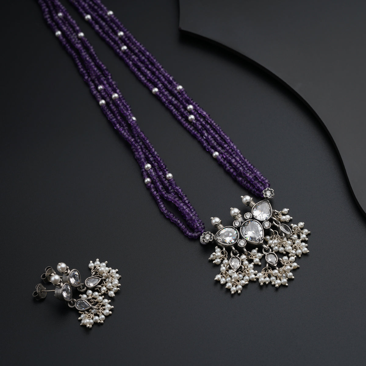 a purple necklace and earring set with pearls