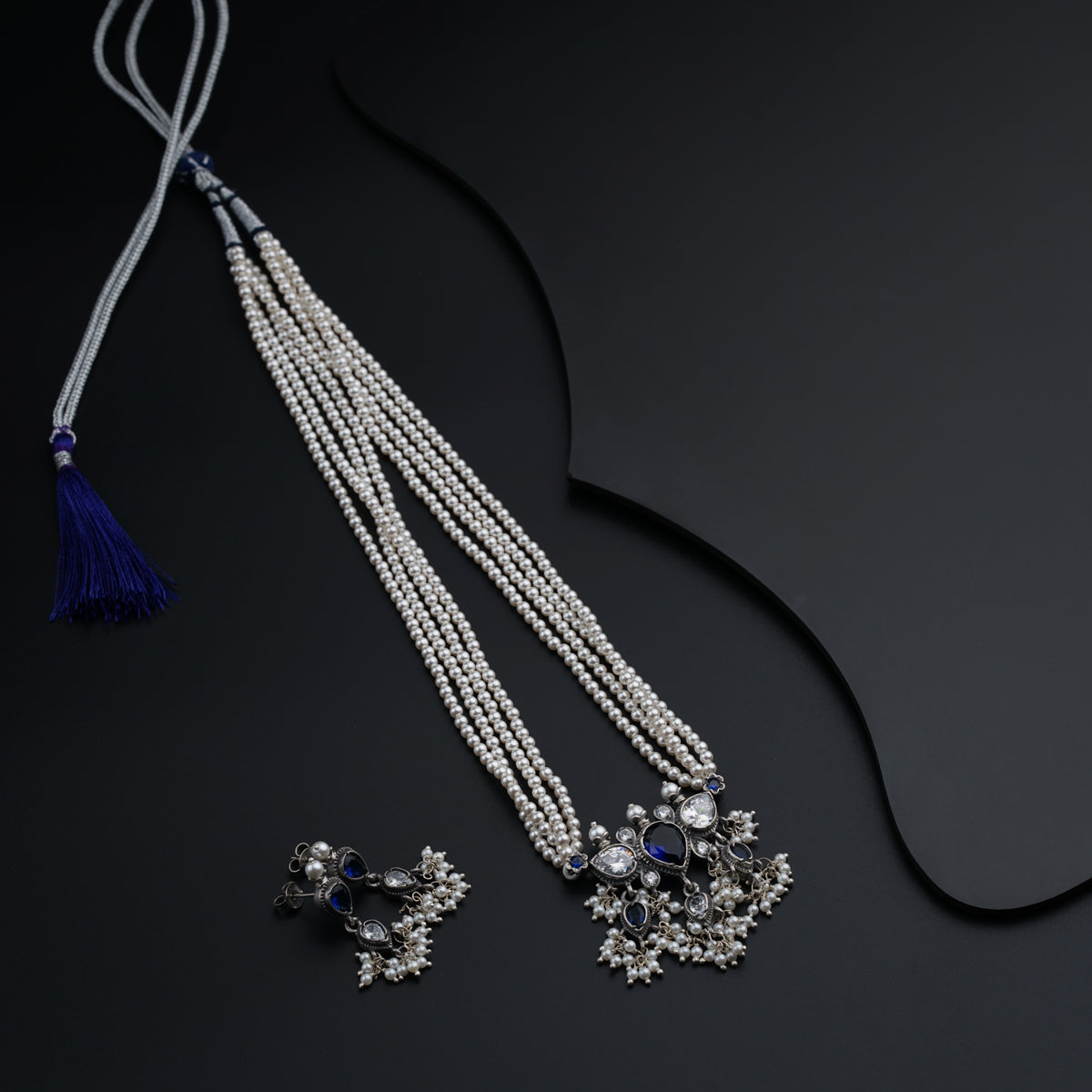 two necklaces with tassels on a black surface
