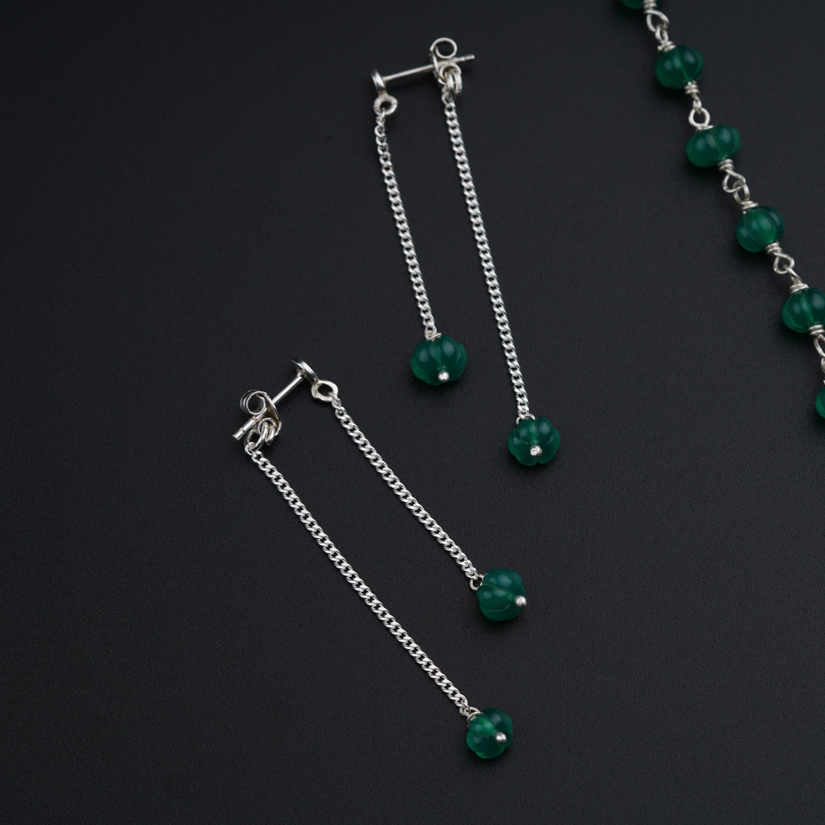 a pair of green beads and chains on a black surface